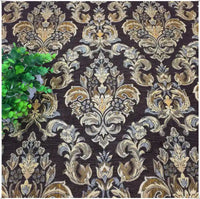 Tissu damassé jacquard au mètre de Longan Craft France (Tissu damassé jacquard au mètre), luxueux tissu damassé chenillé à motifs floraux, présenté avec des motifs beiges, or et crème. Une petite plante verte feuillue apparaît sur la gauche.