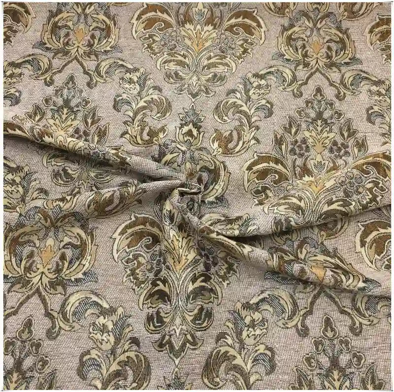 Tissu damassé chenille au mètre de Longan Craft France : un jacquard à motifs floraux et feuillages en or, beige et vert, drapé avec des plis et des plis visibles. Idéal pour l'ameublement raffiné.