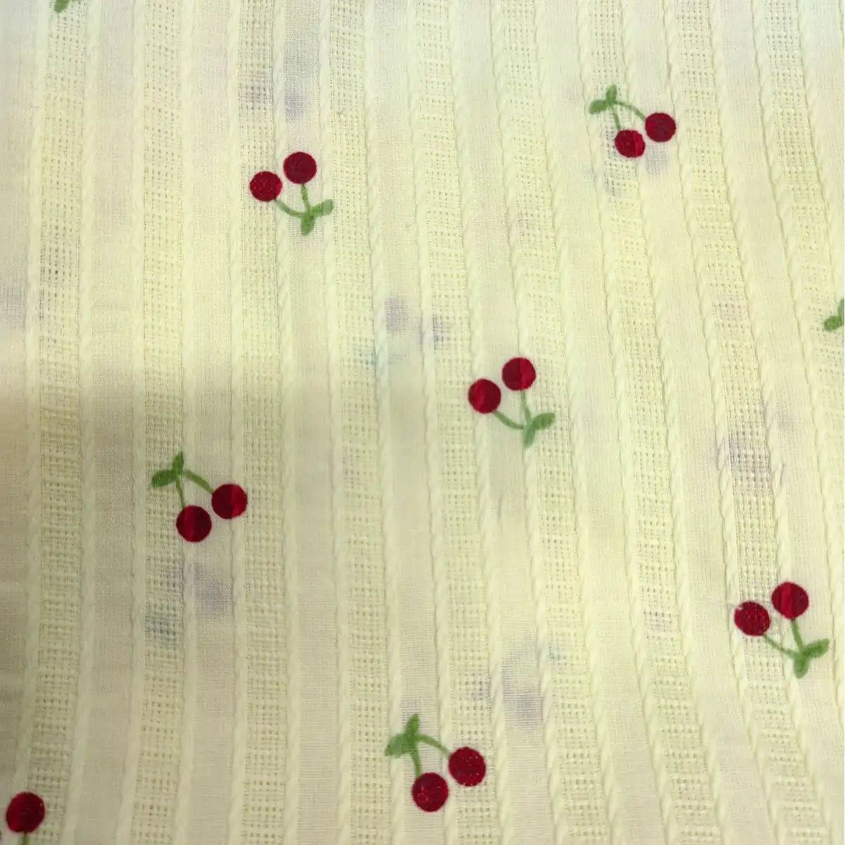 Tissu dobby texturé imprimé cerises au mètre de Longan Craft France : coton léger crème à rayures, décoré de petits motifs de paires de cerises rouges aux tiges vertes, idéal pour vêtements.