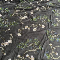 Le tissu coton et soie brodé de style chinois de Longan Craft France est orné de branches d'arbres, de fleurs blanches et d'aiguilles vertes pour un motif botanique élégant, idéal pour chemisiers ou projets haut de gamme.