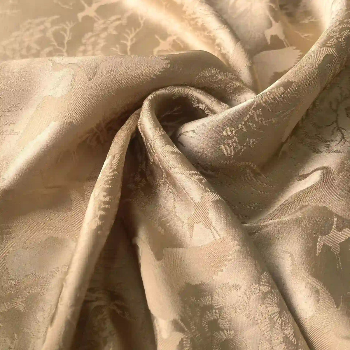 Un gros plan du tissu chinois en polyester-viscose au mètre de Longan Craft France montre le motif jacquard botanique avec des arbres et des cerfs, doucement drapé et froncé pour mettre en valeur sa surface lisse et texturée, idéale pour les rideaux.