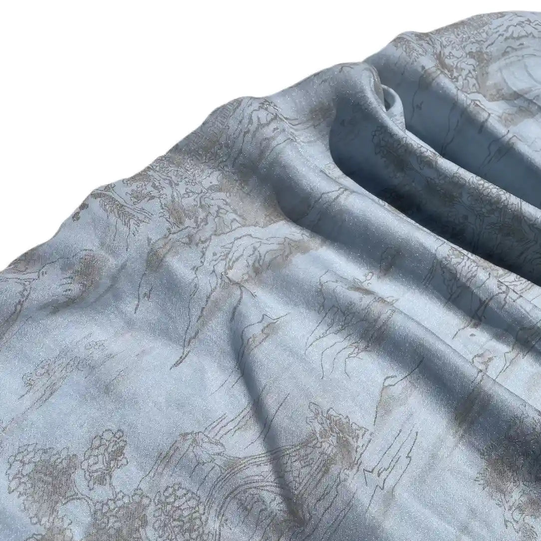 Un gros plan du tissu en lyocell imprimé chinoiserie au mètre de Longan Craft France montre un tissu doux et bleu clair aux motifs délicats, aux plis doux et à la texture lisse, idéal pour la confection de robes.