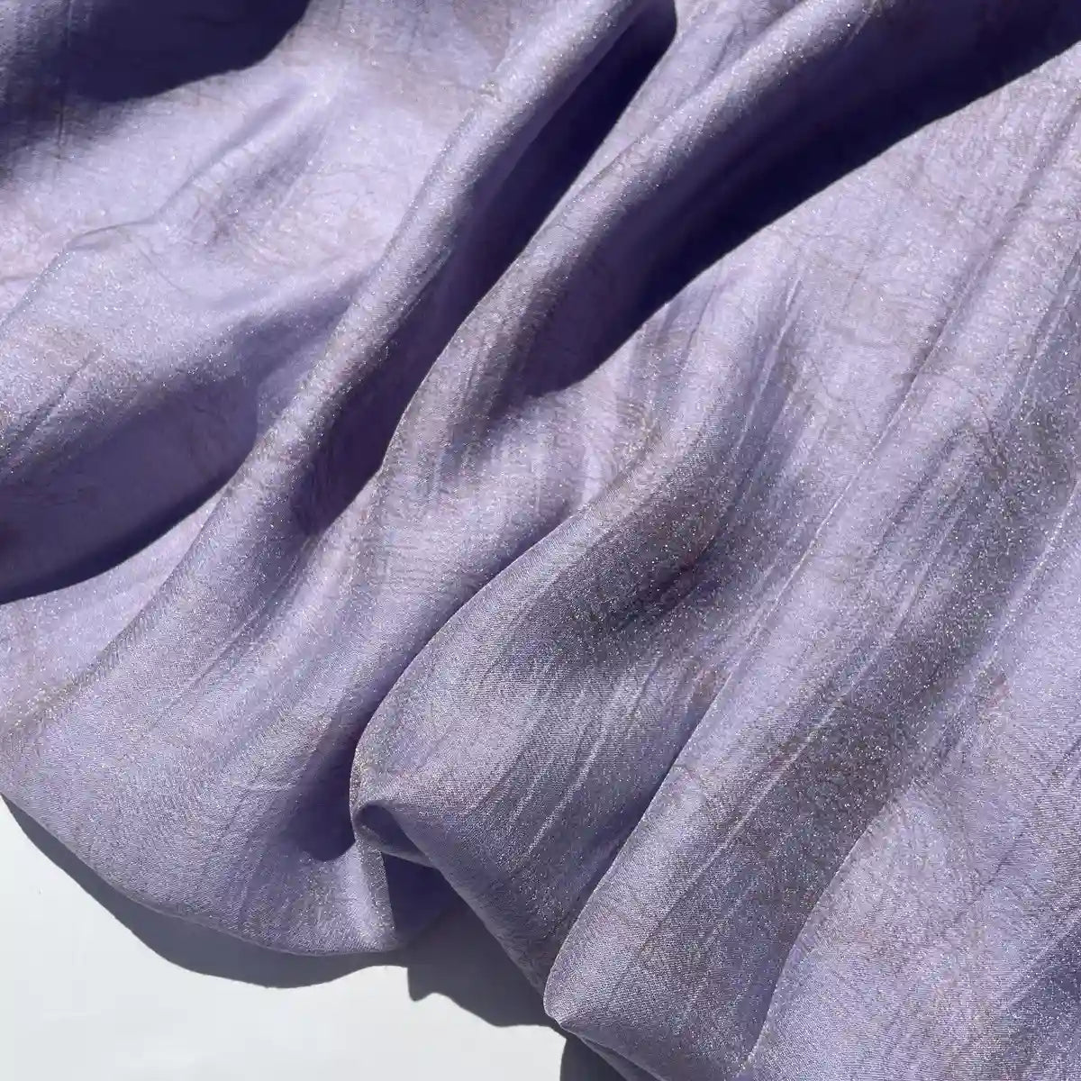 Gros plan sur le tissu lyocell semi-transparent violet clair imprimé chinoiserie par Longan Craft France, montrant sa texture légèrement froissée, sa brillance subtile et son drapé doux, parfait pour la confection de robes.