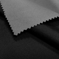 Un Tissu peau de pêche imperméable gris clair enduit au mètre de Longan Craft France avec un bord en zigzag se superpose à un tissu polyester imperméable noir lisse, tous deux montrant la texture du produit pour les vestes.