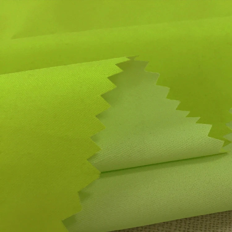 Tissu peau de pêche imperméable enduit au mètre Longan Craft France, microfibre polyester jaune-vert mat, texture douce et chaude à bords zigzag, léger et parfait pour vestes ou vêtements de pluie.