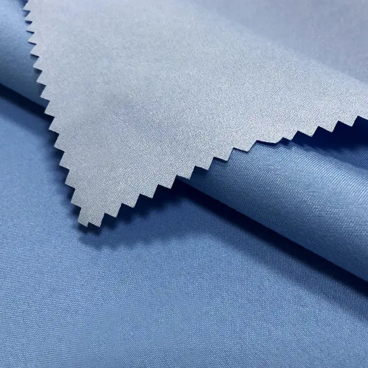 Un gros plan du tissu peau de pêche imperméable enduit au mètre de Longan Craft France montre sa texture douce en microfibre de polyester et son bord en zigzag, idéal pour les vestes chaudes et résistantes à l'eau.
