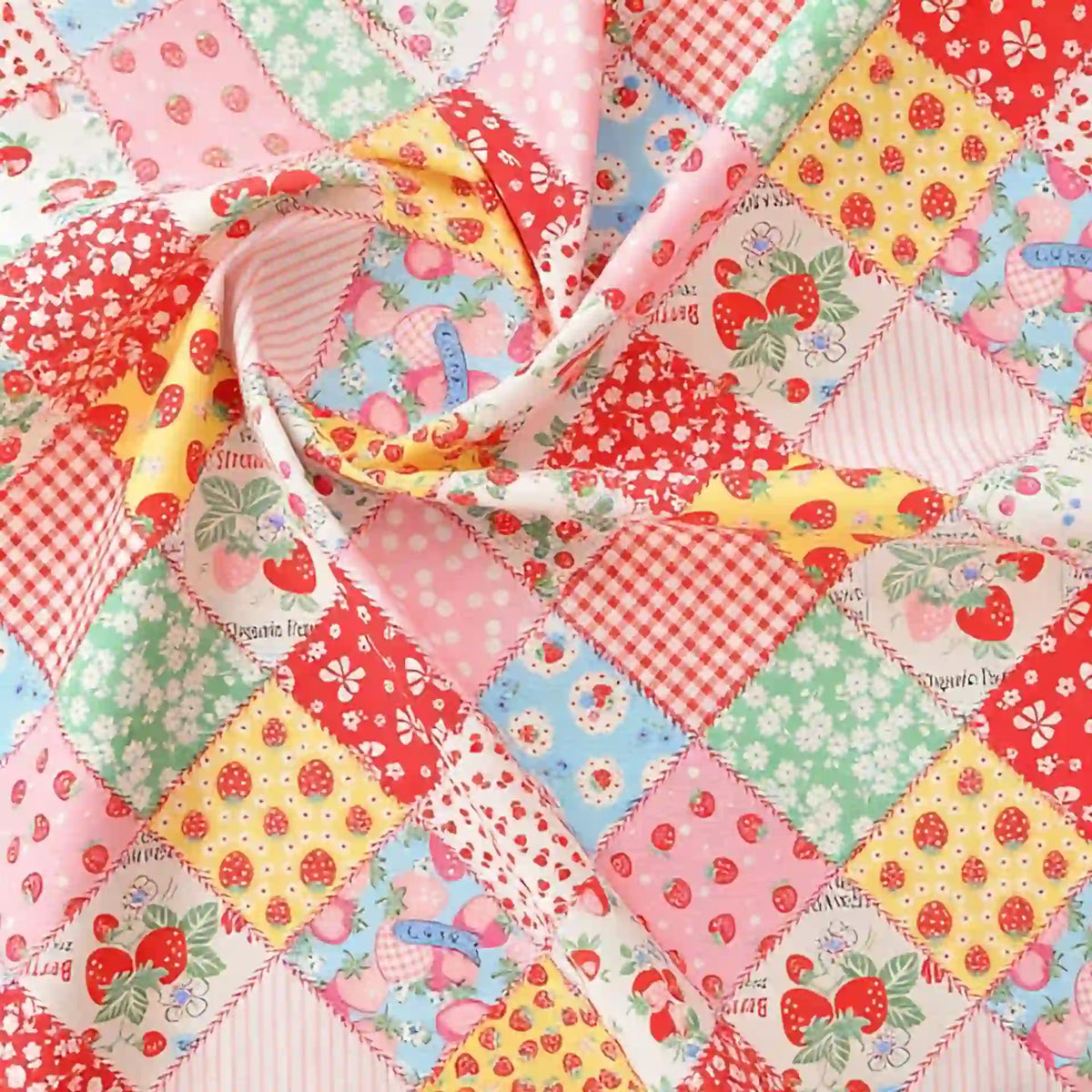 Gros plan sur le tissu popeline imprimé effet patchwork multicolore de Longan Craft France, qui présente des motifs floraux et de fraises dans des couleurs vives. Le tissu de coton destiné à l'habillement est légèrement froncé au centre.