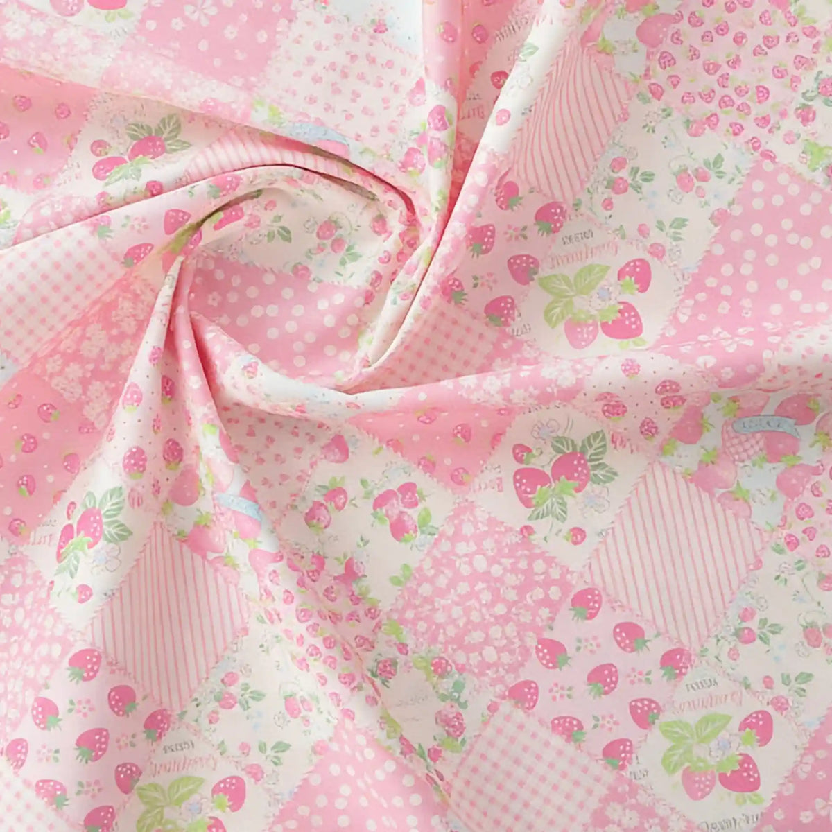 Le tissu popeline imprimé effet patchwork multicolore au mètre de Longan Craft France présente des motifs floraux et de fraises, parfaits pour le patchwork ou l'habillement. Il est ici légèrement torsadé au centre.