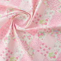 Le tissu popeline imprimé effet patchwork multicolore au mètre de Longan Craft France présente des motifs floraux et de fraises, parfaits pour le patchwork ou l'habillement. Il est ici légèrement torsadé au centre.