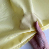 Une main soulève un morceau de Soie de coton multicolore au mètre - légère soie de mûrier de Longan Craft France - illustrant sa texture douce, sa légèreté et son aspect translucide, idéale en tissu de doublure en soie respirant.