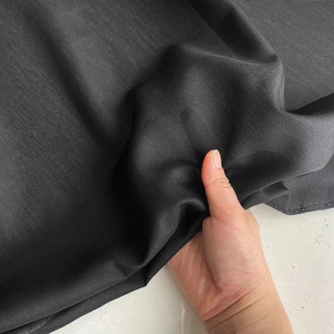 Une main fronce une Soie de coton multicolore au mètre - un tissu léger et respirant de Longan Craft France - sur une surface claire.