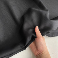 Une main fronce une Soie de coton multicolore au mètre - un tissu léger et respirant de Longan Craft France - sur une surface claire.