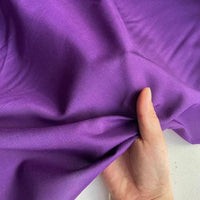 Une main tient un morceau de Soie de coton multicolore au mètre | Soie de mûrier légère de Longan Craft France, lisse et brillant, sur fond clair.