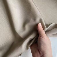 Une main tient un morceau de Soie de coton multicolore au mètre de Longan Craft France, mettant en valeur la texture lisse et le drapé aérien de cette légère soie de mûrier doublure tissu.