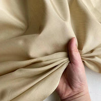 Une main rassemble une section de Soie de coton au mètre multicolore de Longan Craft France, montrant la texture légère de la soie de mûrier - douce, lisse, respirante et subtilement lustrée - idéale pour les doublures et les créations luxueuses.