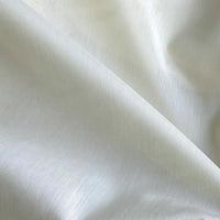 Un gros plan de la Soie de coton multicolore au mètre de Longan Craft France montre des plis délicats et un éclairage doux, mettant en valeur la texture lisse et la légère brillance de ce tissu de doublure en soie de mûrier, léger et respirant.