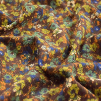 Gros plan sur le Tissu velours côtelé à fleurs colorées au mètre de Longan Craft France, montrant son velours texturé avec des motifs floraux verts, orange, bleus et blancs sur fond marron - parfait pour la confection, l'ameublement ou les loisirs créatifs.