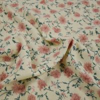 Gros plan sur le tissu velours côtelé à fleurs colorées au mètre de Longan Craft France, montrant sa base crème, son motif floral avec des fleurs roses et des tiges vertes, et sa surface texturée, doucement plissée et froncée au centre.