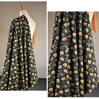 Un tissu velours noir côtelé à fleurs colorées de Longan Craft France est drapé sur un mannequin, montrant son motif floral jaune avec des tiges et des feuilles vertes. Un gros plan met en évidence les détails complexes. Parfait pour la confection, l'ameublement et les loisirs créatifs.