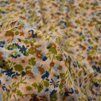 Gros plan sur le Tissu velours côtelé à fleurs colorées au mètre de Longan Craft France, montrant sa surface douce et texturée avec des motifs floraux abstraits verts, bleus et bruns sur un fond clair - idéal pour la confection, l'ameublement ou les loisirs créatifs.