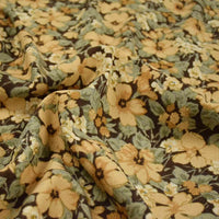 Un gros plan de Tissu velours côtelé à fleurs colorées au mètre de Longan Craft France montre sa texture avec motifs floraux jaunes et beiges, feuilles vertes et fond foncé, idéal pour confection, ameublement et loisirs créatifs.