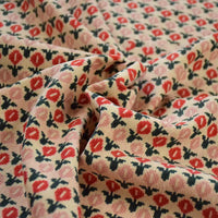 Gros plan sur le tissu velours côtelé à fleurs colorées de Longan Craft France, montrant de petites fleurs rouges et roses avec des feuilles vertes sur un fond beige clair - parfait pour la couture, la décoration et l'artisanat.