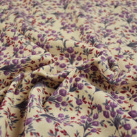 Gros plan sur le Tissu velours côtelé à fleurs colorées de Longan Craft France, avec surface texturée et motif floral violet, rouge et vert, idéal pour confection, ameublement ou loisirs créatifs.
