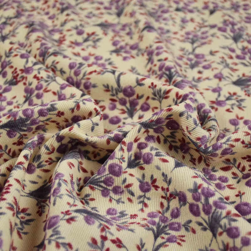 Gros plan sur le Tissu velours côtelé à fleurs colorées de Longan Craft France, avec surface texturée et motif floral violet, rouge et vert, idéal pour confection, ameublement ou loisirs créatifs.