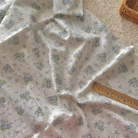 Le Tissu plumetis blanc imprimé de fleurs au mètre de Longan Craft France, en coton doux et motif floral, est parfait pour vos créations couture et vêtements d'intérieur.