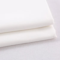 Deux pièces de gabardine polyester rayonne de Longan Craft France, soigneusement pliées, sont empilées sur une surface claire. Ce textile épais, idéal pour le bricolage d'uniformes et de robes, présente une texture lisse et subtilement visible et est vendu au mètre.