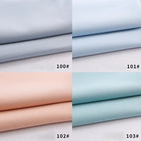 Quatre gabardines Longan Craft France pliées sont représentées : en haut à gauche gris clair (100#), en haut à droite bleu clair (101#), en bas à gauche pêche claire (102#), en bas à droite sarcelle claire (103#) - polyester-rayon épais, idéal pour les uniformes de bricolage.