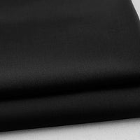 Gros plan sur deux pièces de gabardine polyester-rayonne Tissu noir de Longan Craft France, parfaites pour les uniformes et le bricolage, présentées sur une surface blanche pour mettre en valeur leur texture épaisse et leur qualité de finition.