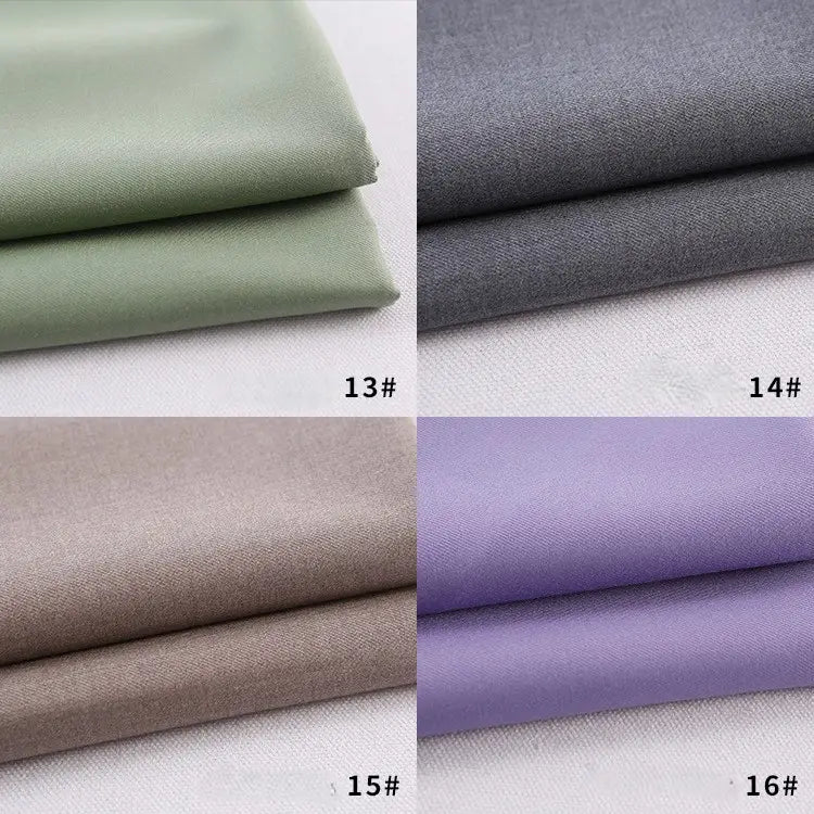 Quatre échantillons de gabardine de Longan Craft France - vert clair (13#), gris (14#), beige (15#) et violet clair (16#) - sont pliés sur une surface blanche, chacun étant fabriqué à partir d'un polyester-rayon épais, idéal pour les uniformes de bricolage.