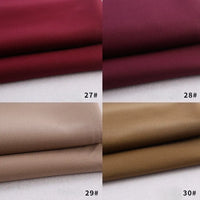 Quatre échantillons de gabardine pliée de Longan Craft France sont présentés en rouge foncé (27#), bordeaux (28#), beige (29#) et beige (30#). Chaque textile coloré en polyester-rayon est présenté sur une surface blanche.