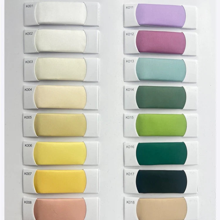 Présentation de 18 échantillons de tissu satiné en viscose (K001-K018) de Longan Craft France, disposés en deux colonnes. Le Tissu satiné coloré en viscose au mètre présente des nuances élégantes allant du blanc à la pêche, idéales pour les robes de cérémonie.