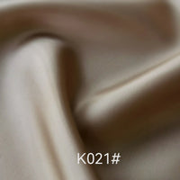 Gros plan sur un élégant tissu en satin de viscose beige de Longan Craft France, au lustre doux et aux plis subtils. Le code "K021#" est affiché en bas au centre. Parfait pour les robes d'occasions spéciales ; disponible au mètre.