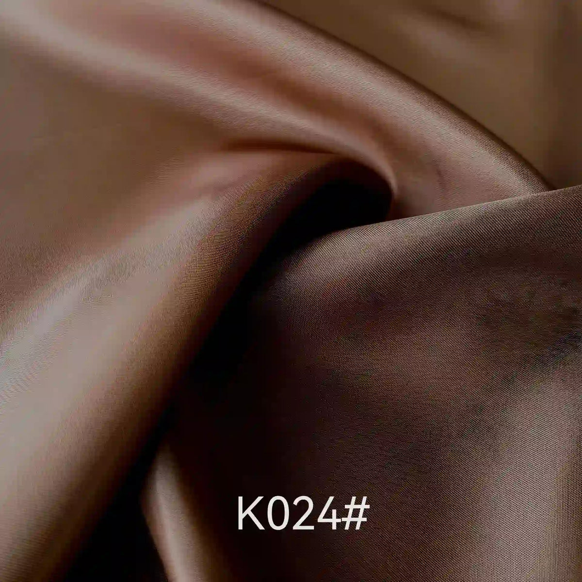 Un gros plan du tissu satiné coloré en viscose au mètre de Longan Craft France présente des plis et reflets lustrés. Le code K024# apparaît en bas au centre, illustrant cette élégante viscose idéale pour robes de cérémonie.
