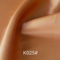 Gros plan sur un tissu satiné coloré en viscose au mètre de Longan Craft France, lisse et brillant, délicatement plié. Le code "K025#" figure en bas au centre. Idéal pour les robes élégantes et les occasions spéciales.