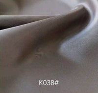 Gros plan sur le tissu satiné coloré en viscose au mètre de Longan Craft France, aux plis doux et à la texture moelleuse. Tissage sergé polyester-viscose, élégant pour les robes de cérémonie. Code "K038#" en bas au centre.