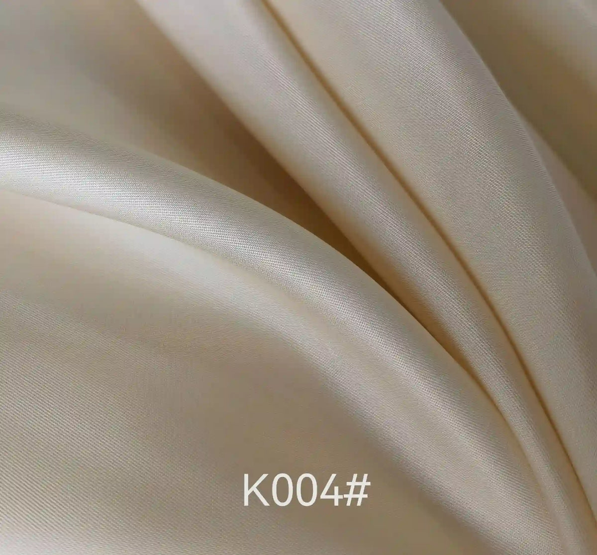 Gros plan sur le tissu satiné coloré en viscose au mètre de Longan Craft France, aux plis doux et à la texture brillante et soyeuse - idéal pour les robes de cérémonie. La mention "K004#" apparaît en bas au centre de l'image.