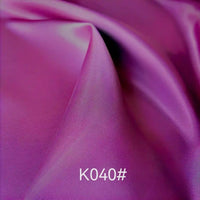 Gros plan sur le Tissu satiné coloré en viscose au mètre (Tissage sergé polyester-viscose) de Longan Craft France, aux plis délicats. La mention "K040#" apparaît en bas au centre. Idéal pour les robes de cérémonie élégantes.