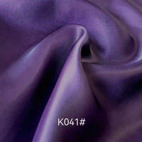 Gros plan sur le tissu satiné coloré en viscose au mètre, tissage sergé polyester-viscose de Longan Craft France. La texture soyeuse et élégante avec des plis est parfaite pour les robes de cérémonie. Le code "K041#" apparaît en bas au centre.