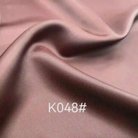 Tissu satiné viscose rose-brun lisse et brillant de Longan Craft France, idéal pour les robes de cérémonie. Tissage sergé polyester-viscose avec plis doux et code "K048#" imprimé en bas au centre.