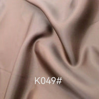 Gros plan sur un tissu satiné coloré en viscose au mètre de Longan Craft France, aux plis souples et à la brillance subtile. La mention "K049#" apparaît en blanc en bas au centre de l'image.