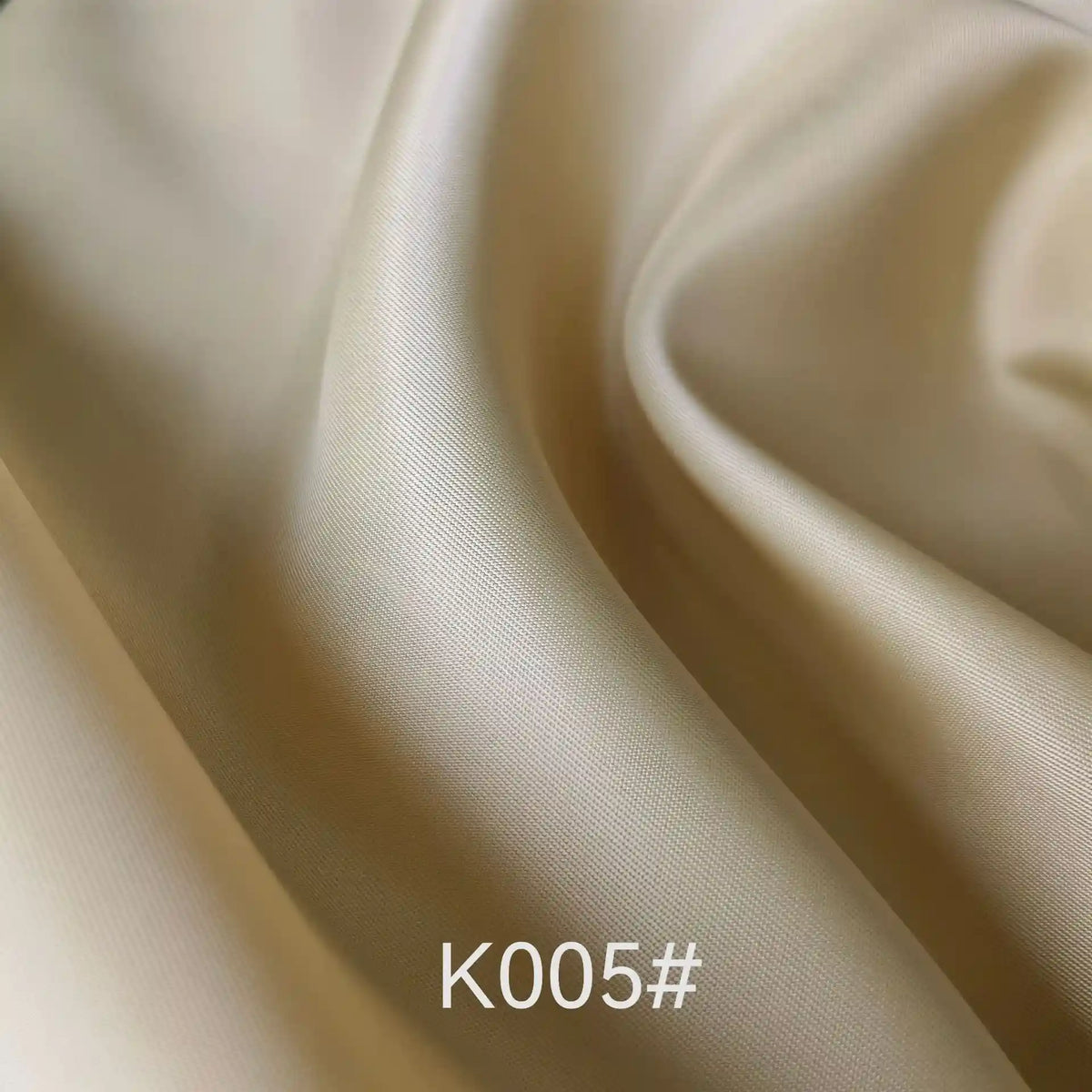 Gros plan sur un tissu beige satiné coloré en viscose au mètre de Longan Craft France, montrant des plis subtils et une légère brillance. Le texte "K005#" apparaît en bas au centre de l'image.