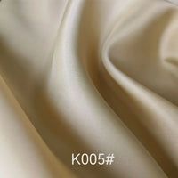Gros plan sur un tissu beige satiné coloré en viscose au mètre de Longan Craft France, montrant des plis subtils et une légère brillance. Le texte "K005#" apparaît en bas au centre de l'image.