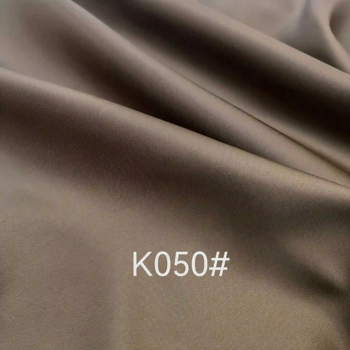 Tissu satiné en viscose marron lisse de Longan Craft France, avec un drapé doux et "K050#" en blanc au centre-tissu satiné coloré en viscose au mètre, idéal pour robes de cérémonie.