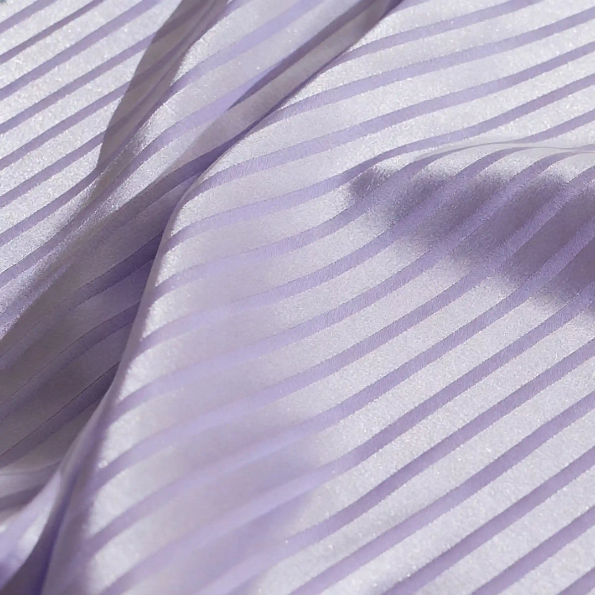 Gros plan sur le Tissu satin jacquard rayé coloré au mètre de Longan Craft France, montrant des motifs rayés brillants et des plis lisses-matière satinée idéale pour confection de robes.