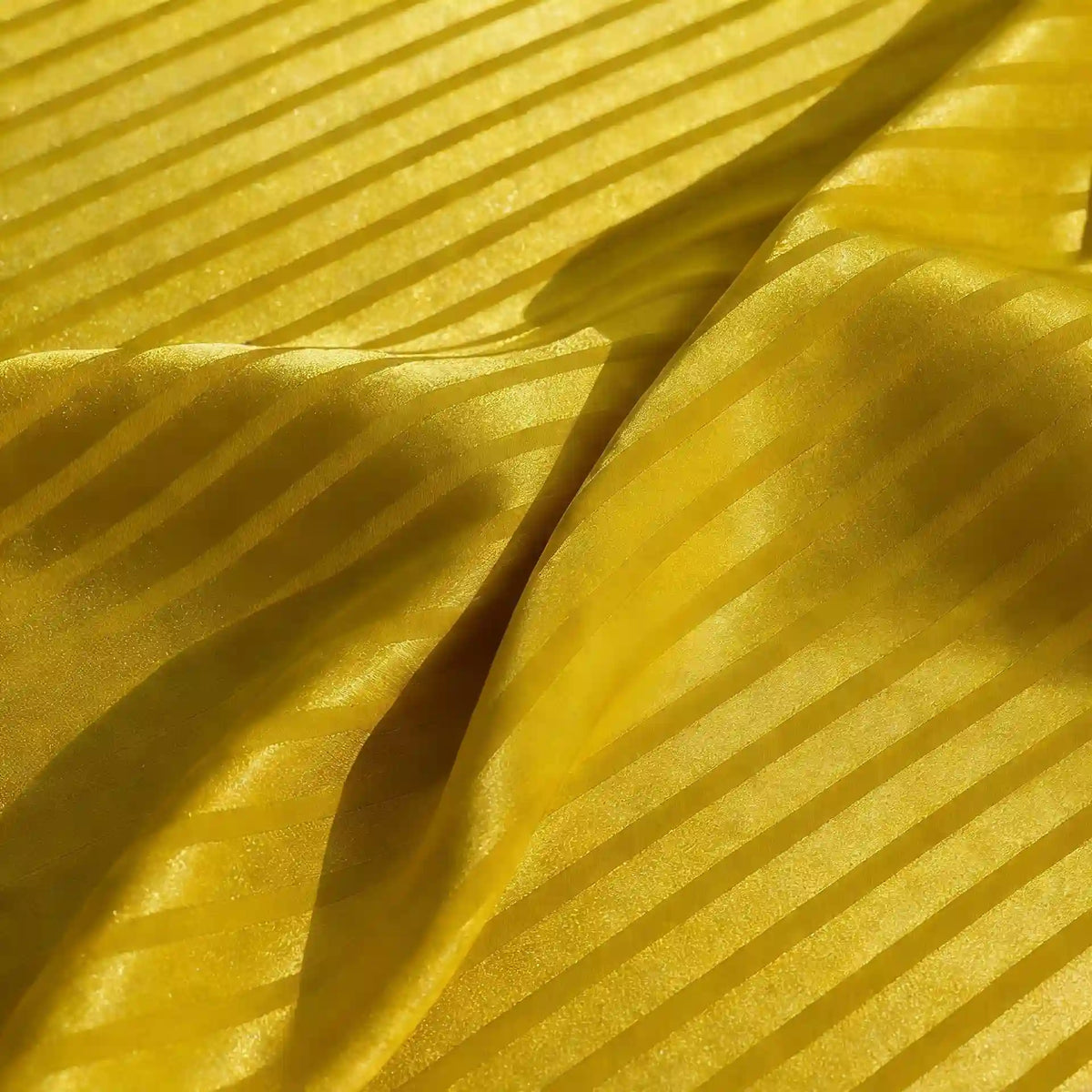 Un gros plan du tissu satin jacquard rayé coloré de Longan Craft France montre des rayures brillantes et mates. Le tissu de satin légèrement froissé crée des plis et des ombres douces, parfaites pour la couture.