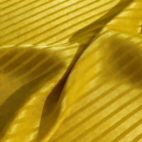 Un gros plan du tissu satin jacquard rayé coloré de Longan Craft France montre des rayures brillantes et mates. Le tissu de satin légèrement froissé crée des plis et des ombres douces, parfaites pour la couture.